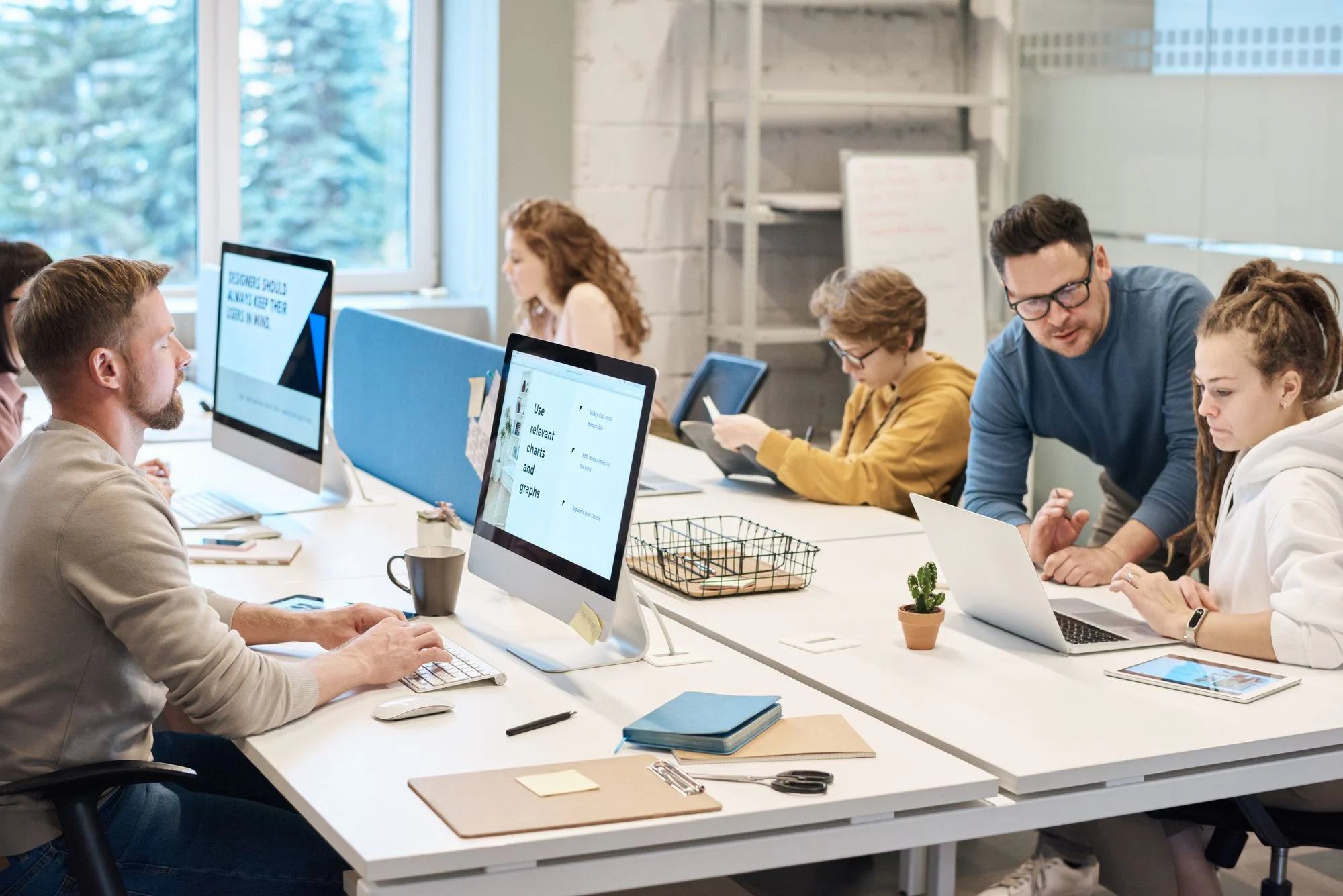 Colleagues working at computers around a shared office table